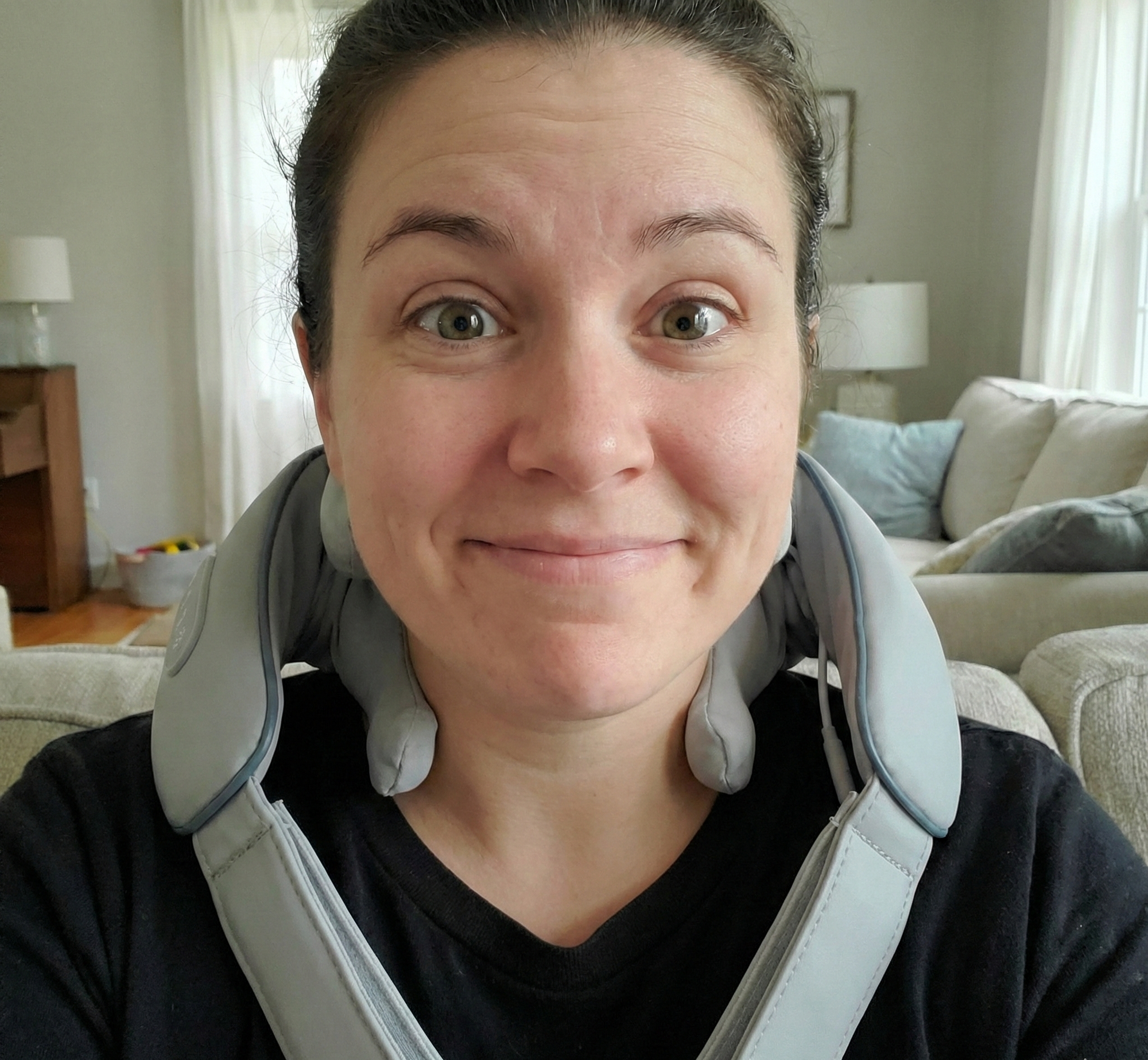 Woman relaxing on sofa at night using a Zenora cordless neck massager with heat for sleep prep.